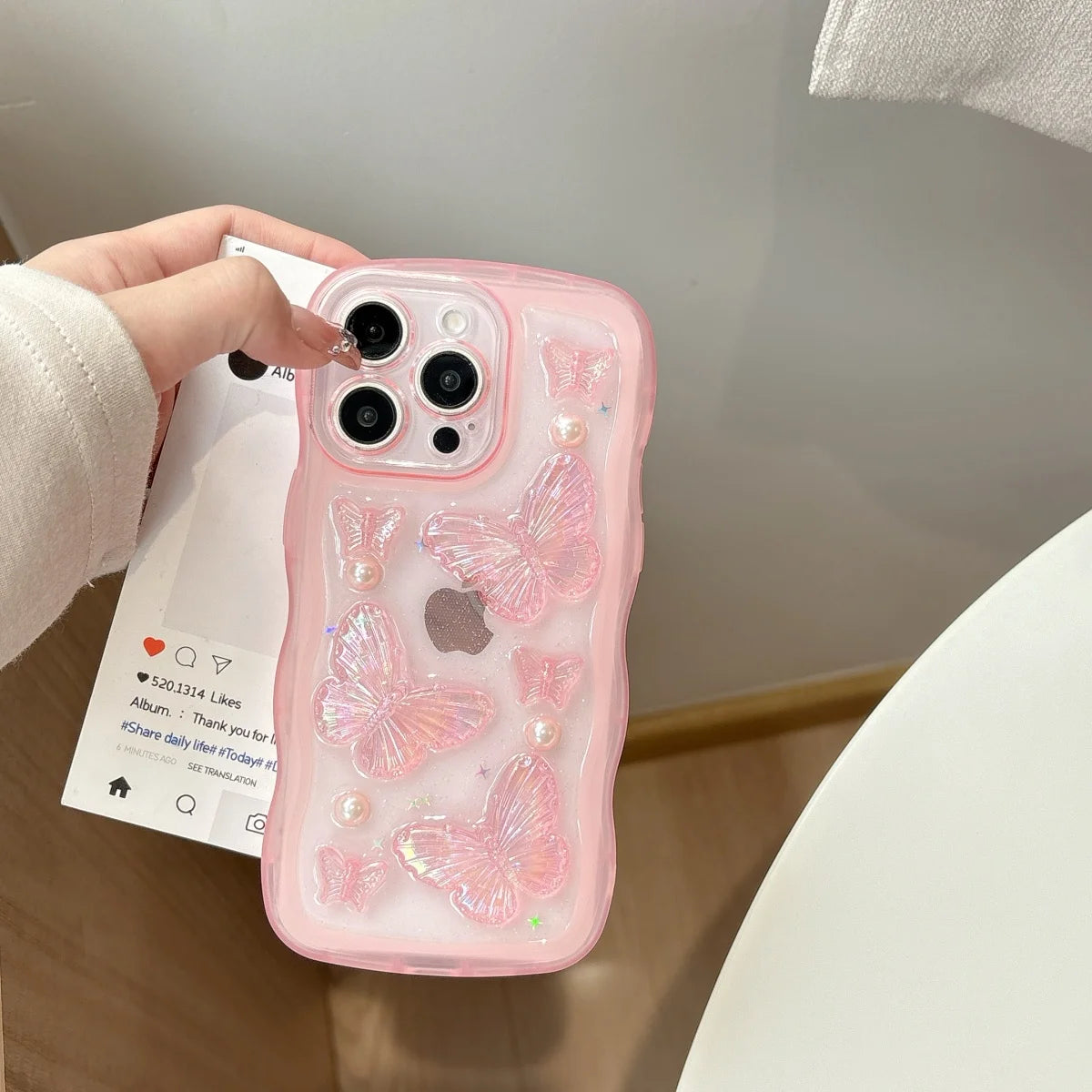 Pink phone case with kawaii butterfly design held by a hand on a light background