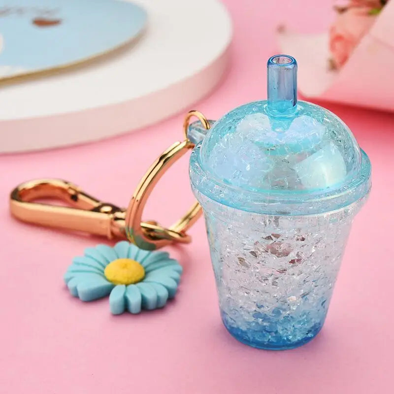Blue glittery cup kawaii keychain with a matching flower charm on a pink background