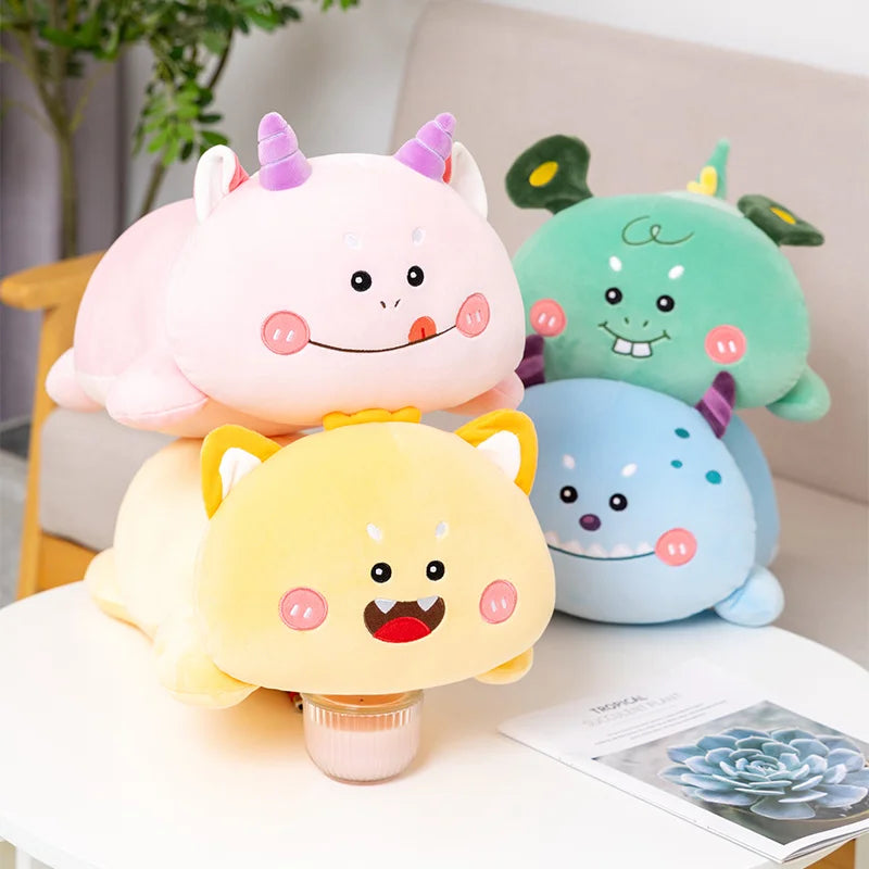 Four colorful kawaii plush toys stacked on a table with a plant and book in the background.