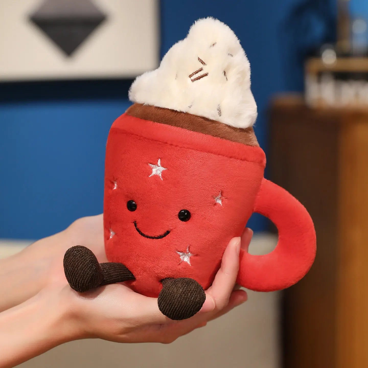 Red plush kawaii toy shaped like a hot chocolate mug with whipped cream held in a hand.