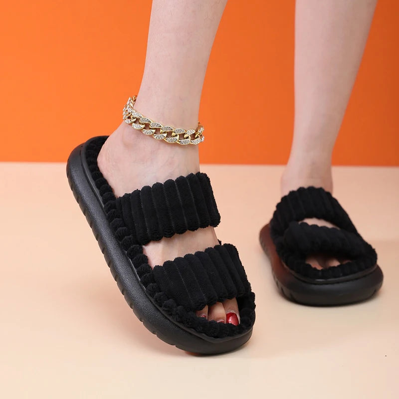 Black kawaii sandals worn with a gold chain bracelet on an orange and beige background