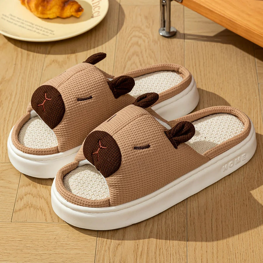 Pair of brown kawaii capybara-shaped slippers on a wooden floor.
