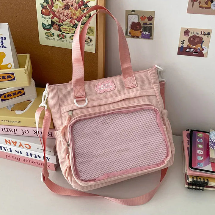 Pink Kawaii bag with a mesh pocket on a surface with books and a phone in the background