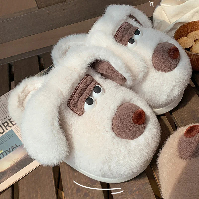 Pair of white kawaii slippers with brown accents resembling animal faces on a wooden surface.