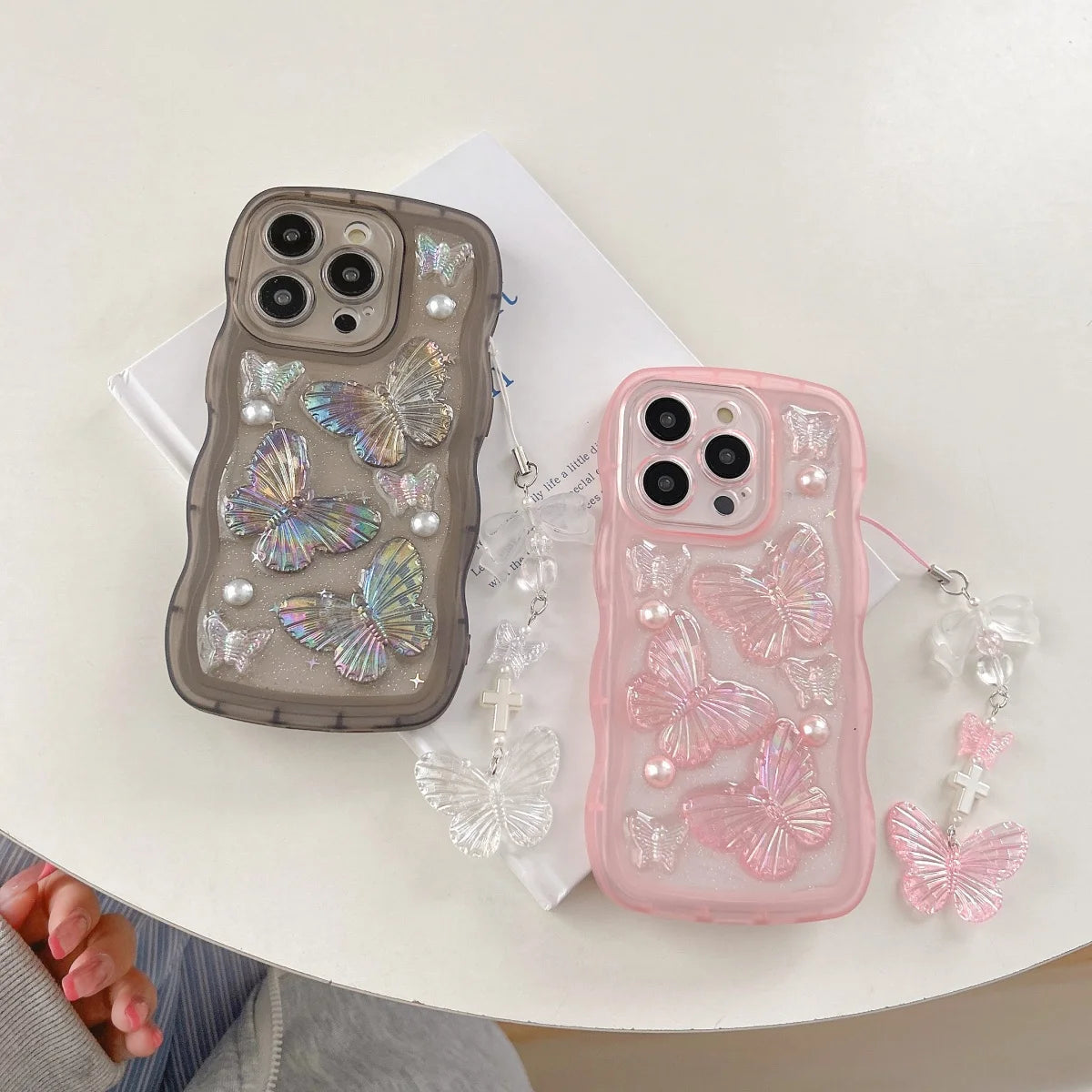 Two kawaii phone cases with butterfly designs on a white surface