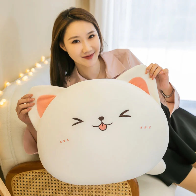 Woman holding a large, round, white pillow with a kawaii cartoon face design.