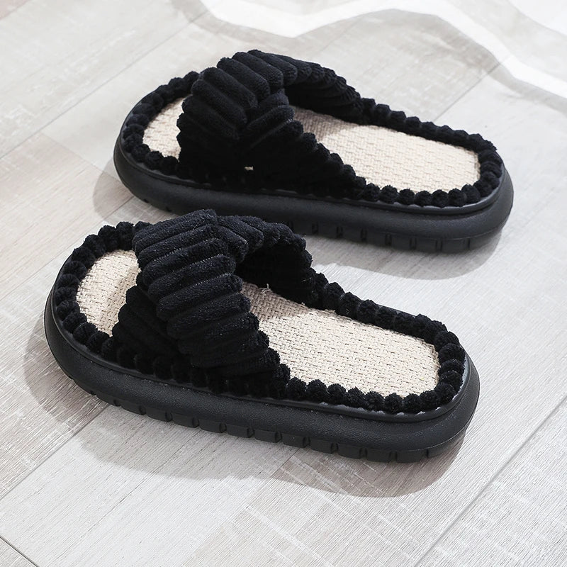Pair of black fuzzy kawaii slippers on a light wooden floor.