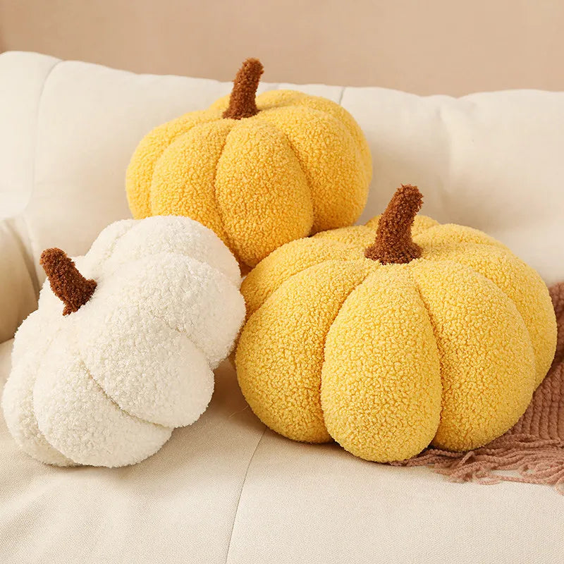 Three kawaii plush pumpkin toys in yellow, white, and a mix of both on a beige couch.