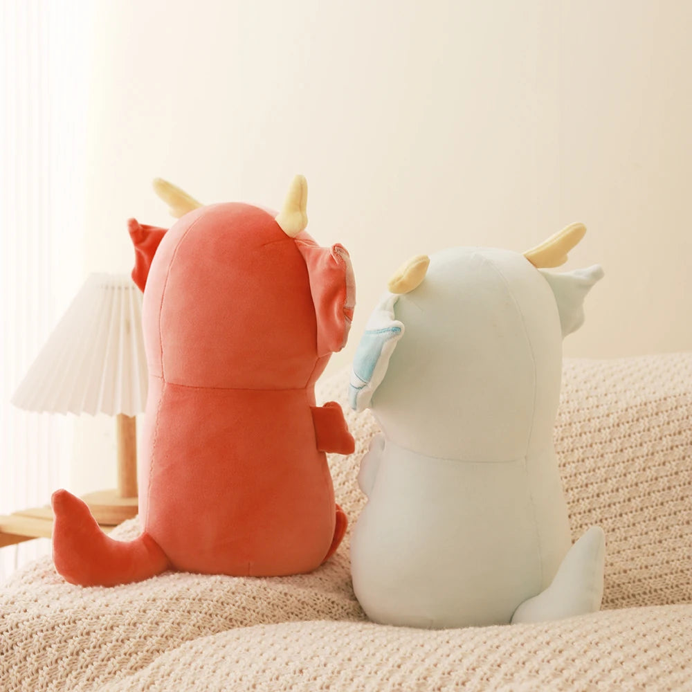 Two kawaii plush toys, one orange and one white, sitting on a textured surface with a neutral background.