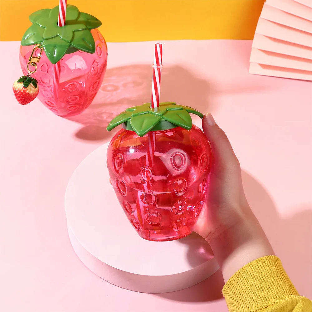Kawaii strawberry-shaped drink container with a hand holding it on a pink background