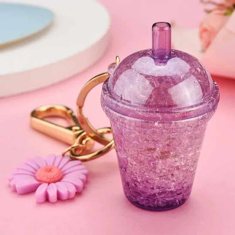 Purple glittery kawaii cup with straw and keychain on a pink background