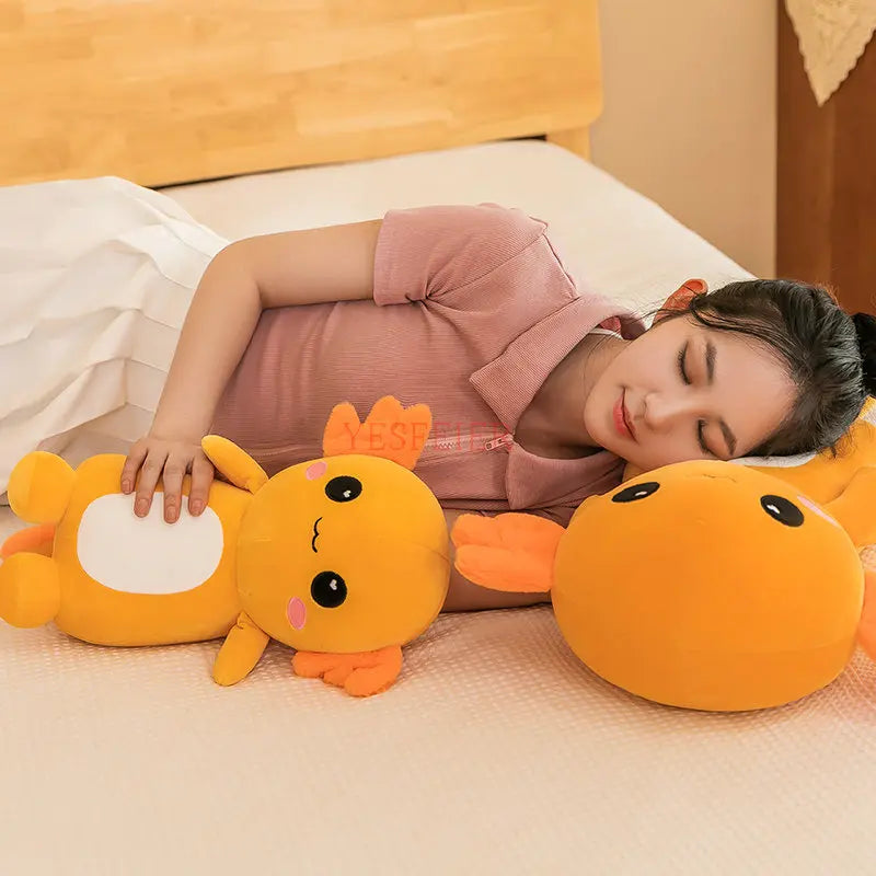 Person lying on a bed with cartoonish kawaii plush toys shaped like fish and a dragon.