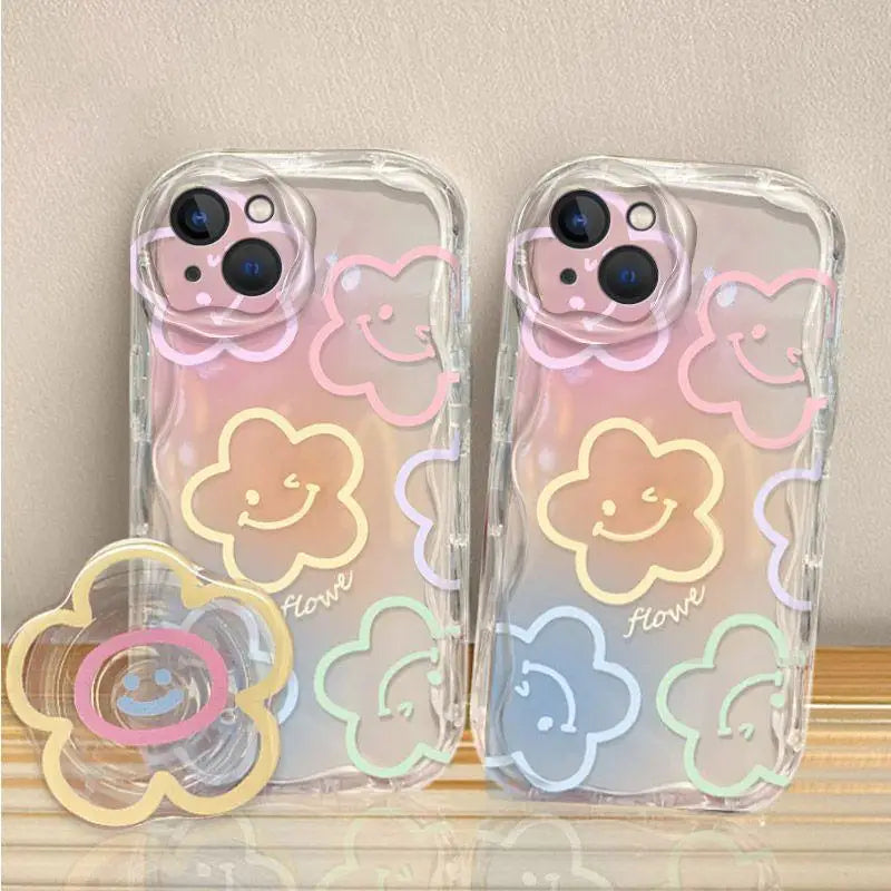Two clear phone cases with colorful kawaii flower designs on a wooden surface.