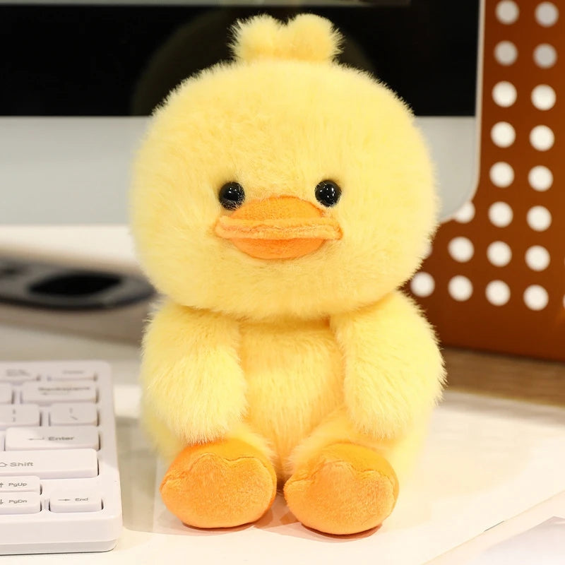 Yellow plush duck kawaii toy on a desk with a keyboard and decorative item in the background