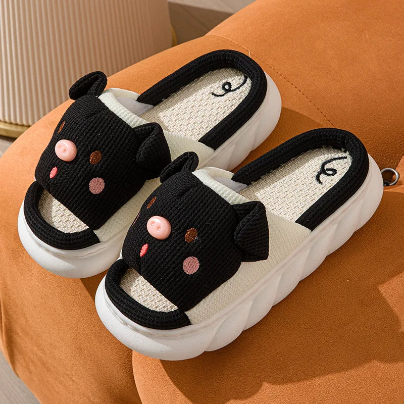Pair of black and white kawaii cat-themed slippers on an orange surface