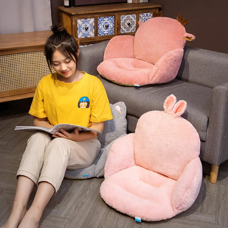 Woman reading a book on the floor with pink animal-shaped kawaii cushions around her.