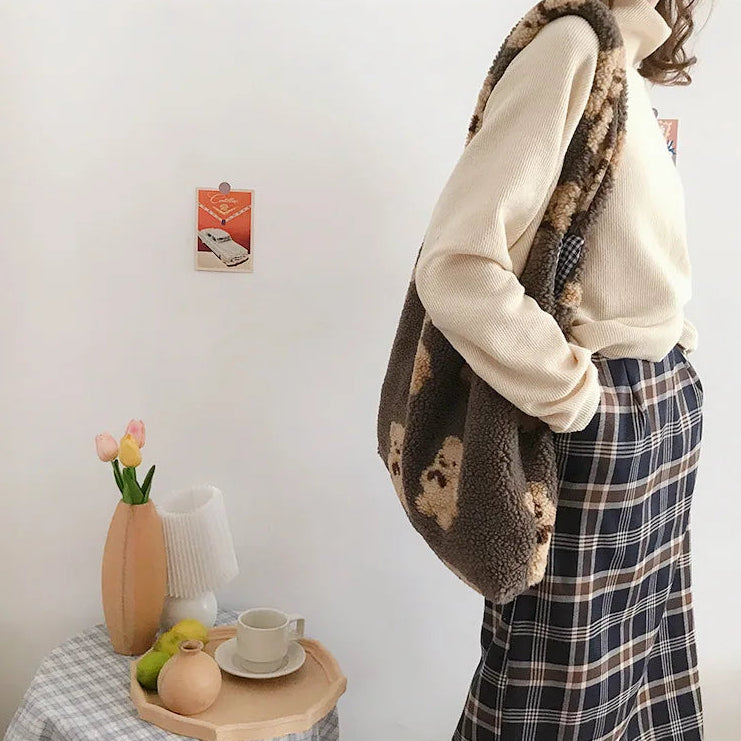 Person wearing a kawaii fluffy brown coat in a room with a small table and decor items.