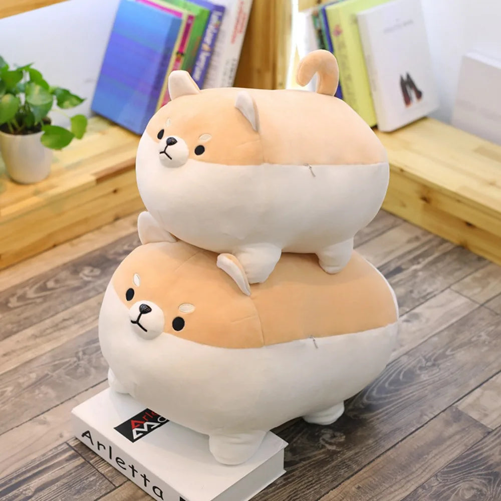 Two stacked plush kawaii toys resembling corgis on a wooden floor with books and a plant in the background.