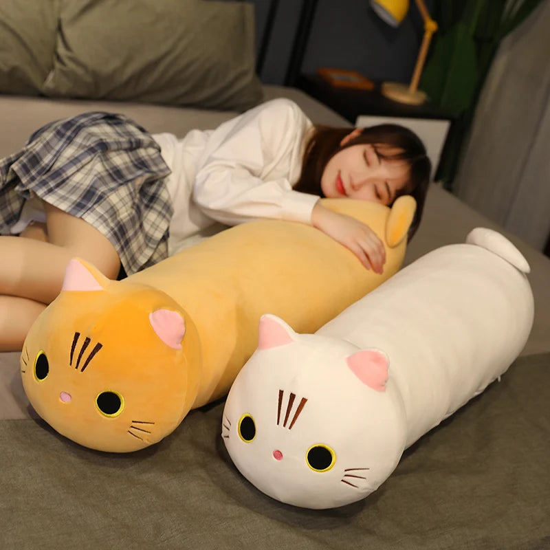 Person lying on a couch with two cat-shaped kawaii cushions, one yellow and one white.
