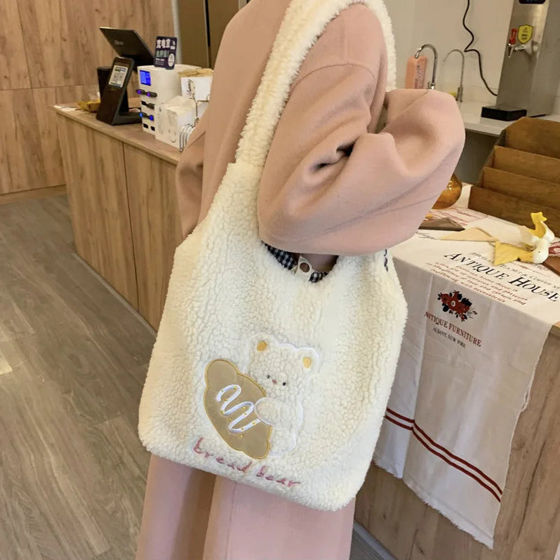 Fluffy white bag with kawaii bear design held by a person in a store setting