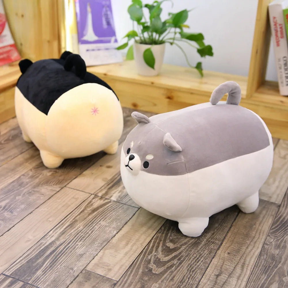 Two cartoon-style plush kawaii toys on a wooden floor with a plant and books in the background.
