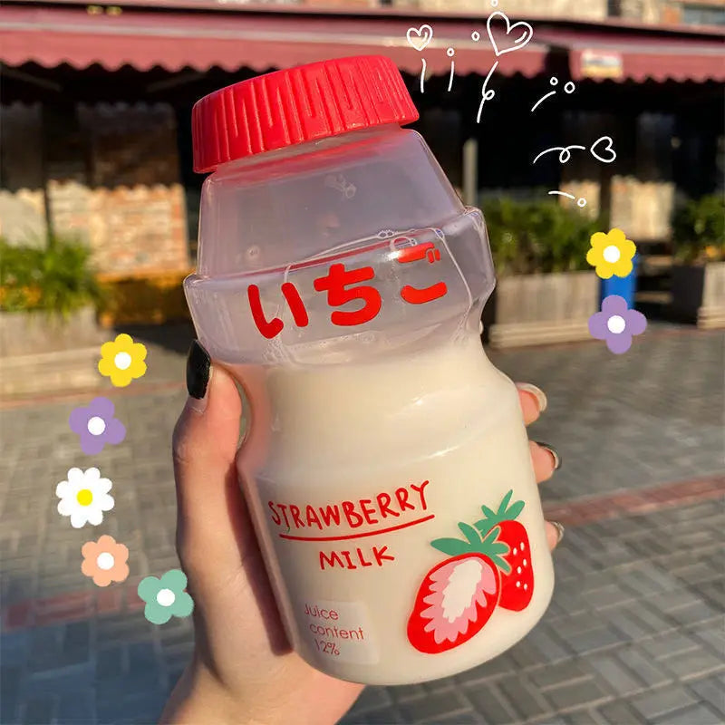 Kawaii strawberry milk bottle held by a hand with decorative elements on a blurred street background