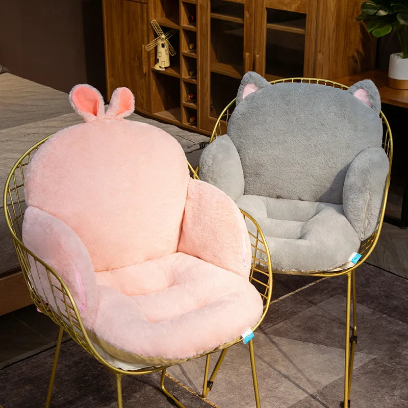 Two plush animal-shaped kawaii cushions, one pink and one gray, on gold wire chairs in a room setting.
