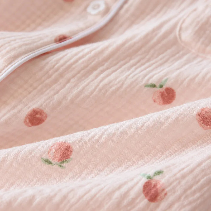 Close-up of a pink textured fabric with embroidered peach kawaii designs.