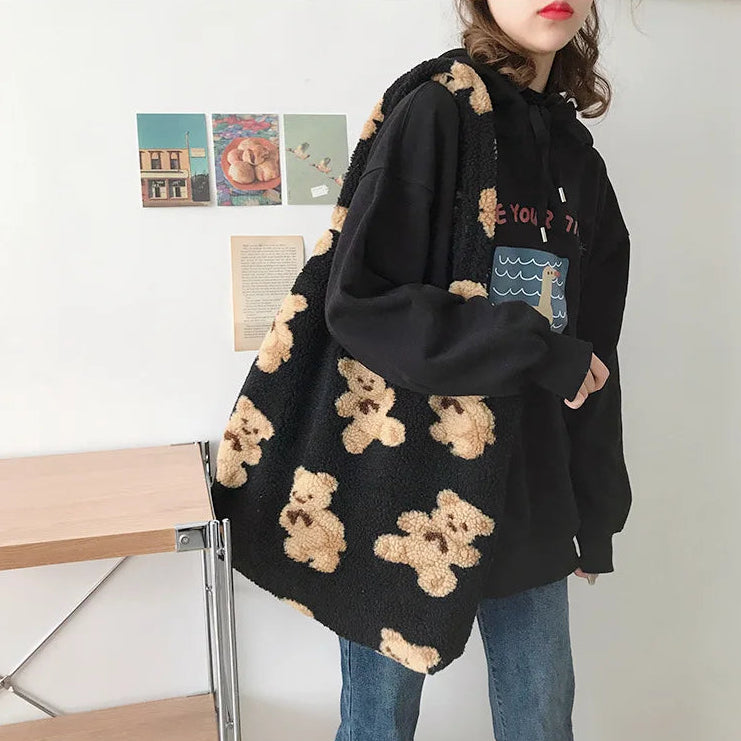 Person wearing a black hoodie with kawaii teddy bear patterns in a casual setting.