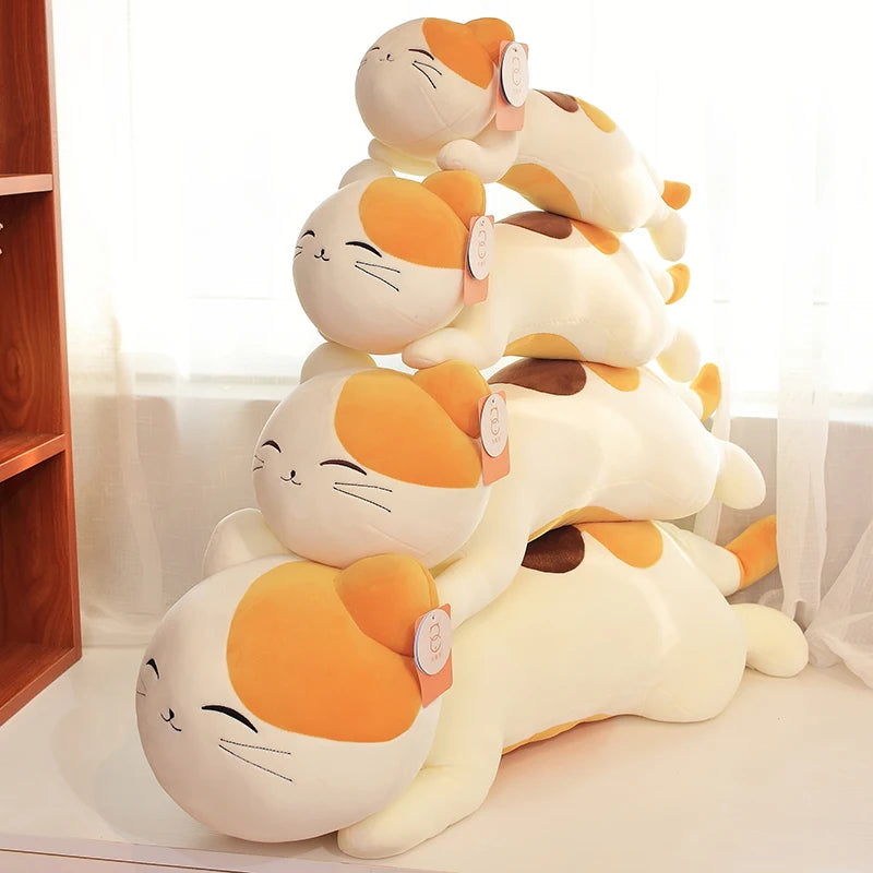 Stack of kawaii cartoon cat plush toys on a white surface with a wooden shelf in the background.