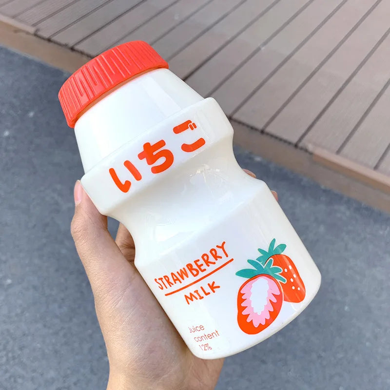 Hand holding a Kawaii strawberry milk bottle with a red cap and Japanese text.