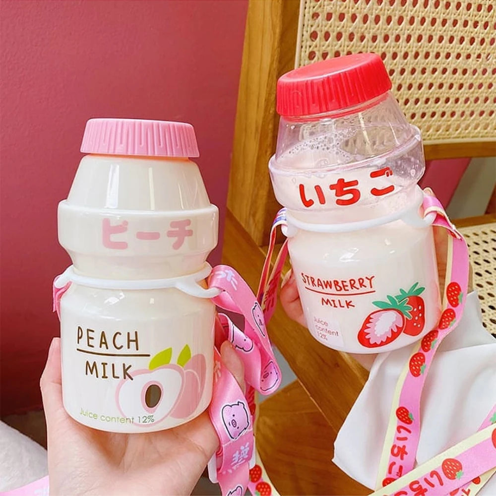 Two small Kawaii-style bottles of peach and strawberry milk with colorful labels and pink straps.