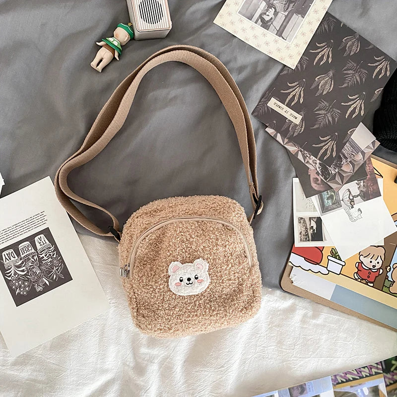 Brown plush bag with a Kawaii bear emblem on a bed with books and photos.