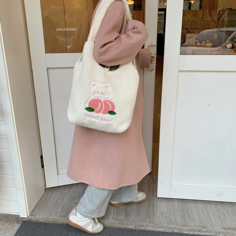 Person wearing a pink coat and holding a white bag with a kawaii cat design, standing in front of a door.