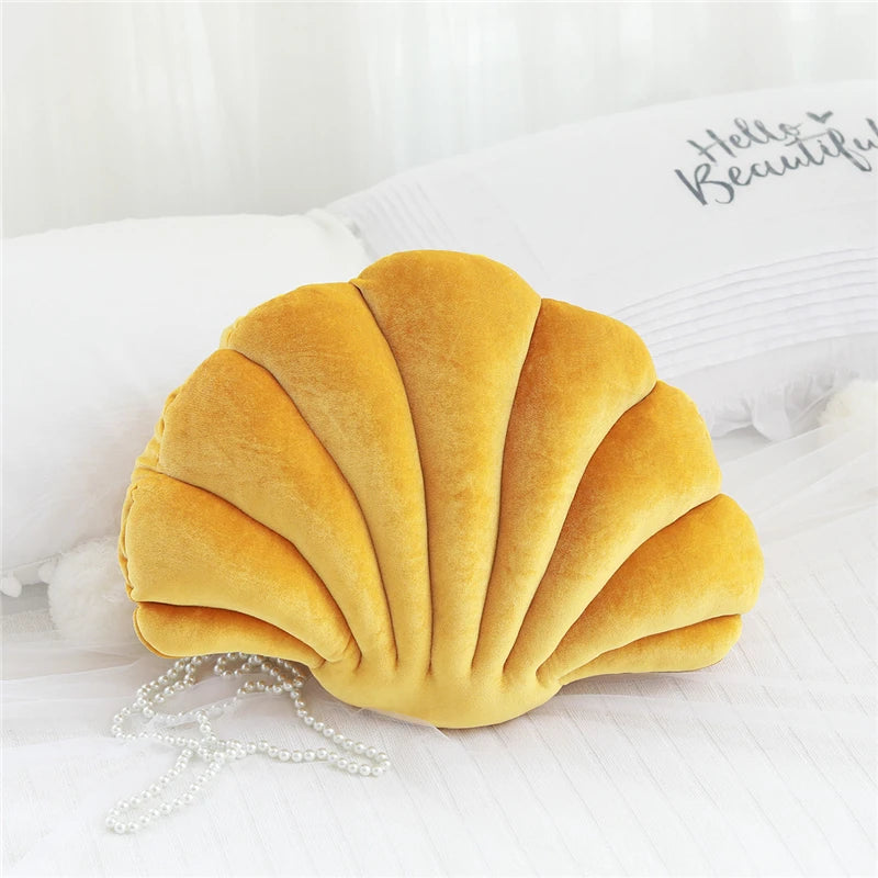Yellow shell-shaped kawaii pillow on a white surface with a blurred background