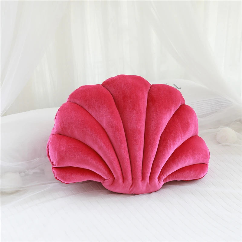 Pink shell-shaped kawaii pillow on a white bed
