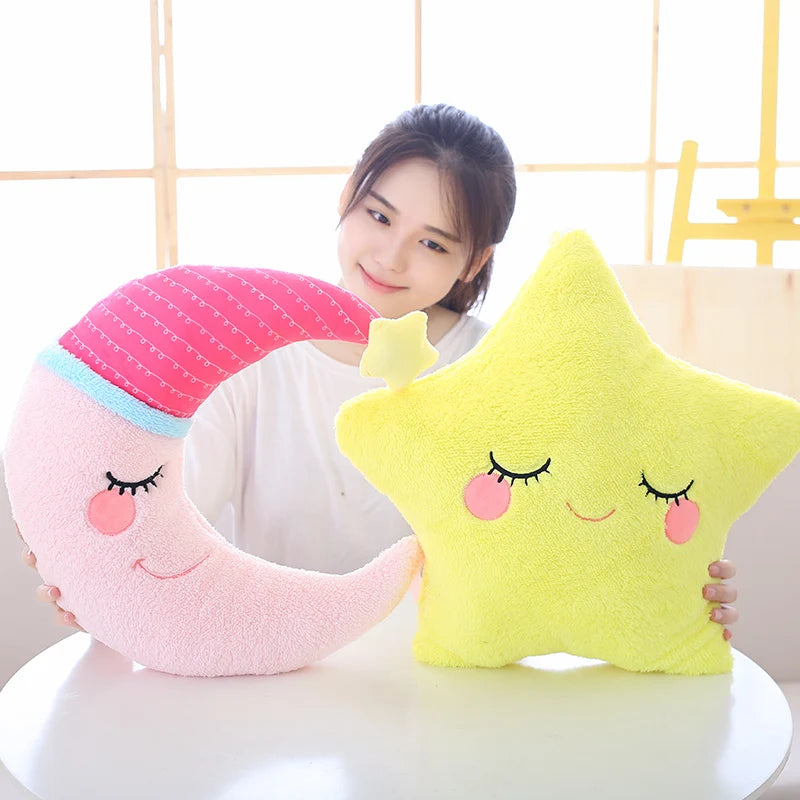 Person holding a pink moon-shaped and yellow star-shaped kawaii plush toy against a white background