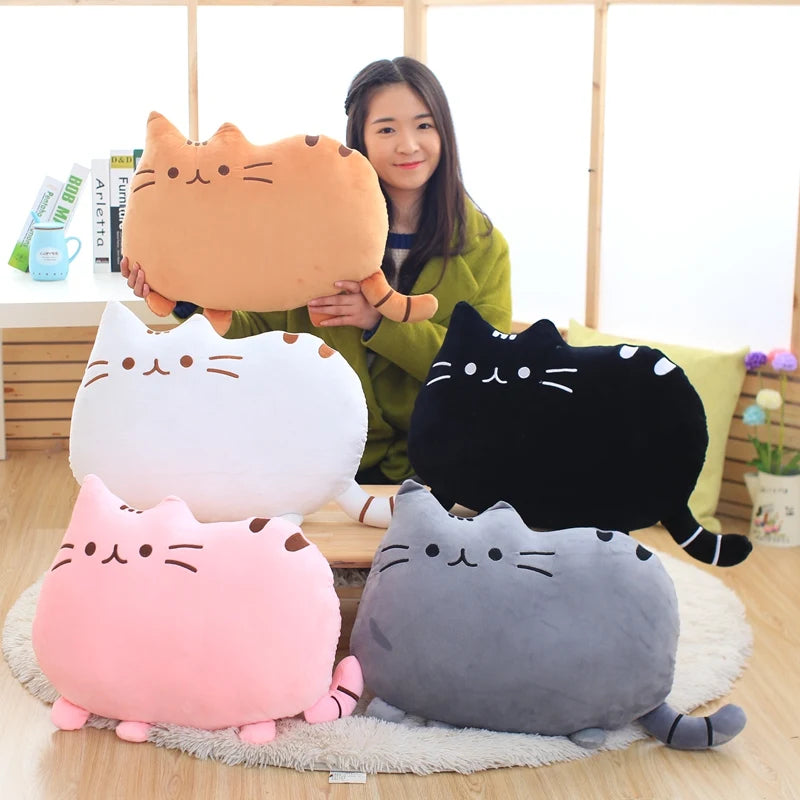 Woman holding a large cat-shaped kawaii pillow with four other cat-shaped pillows on the floor.