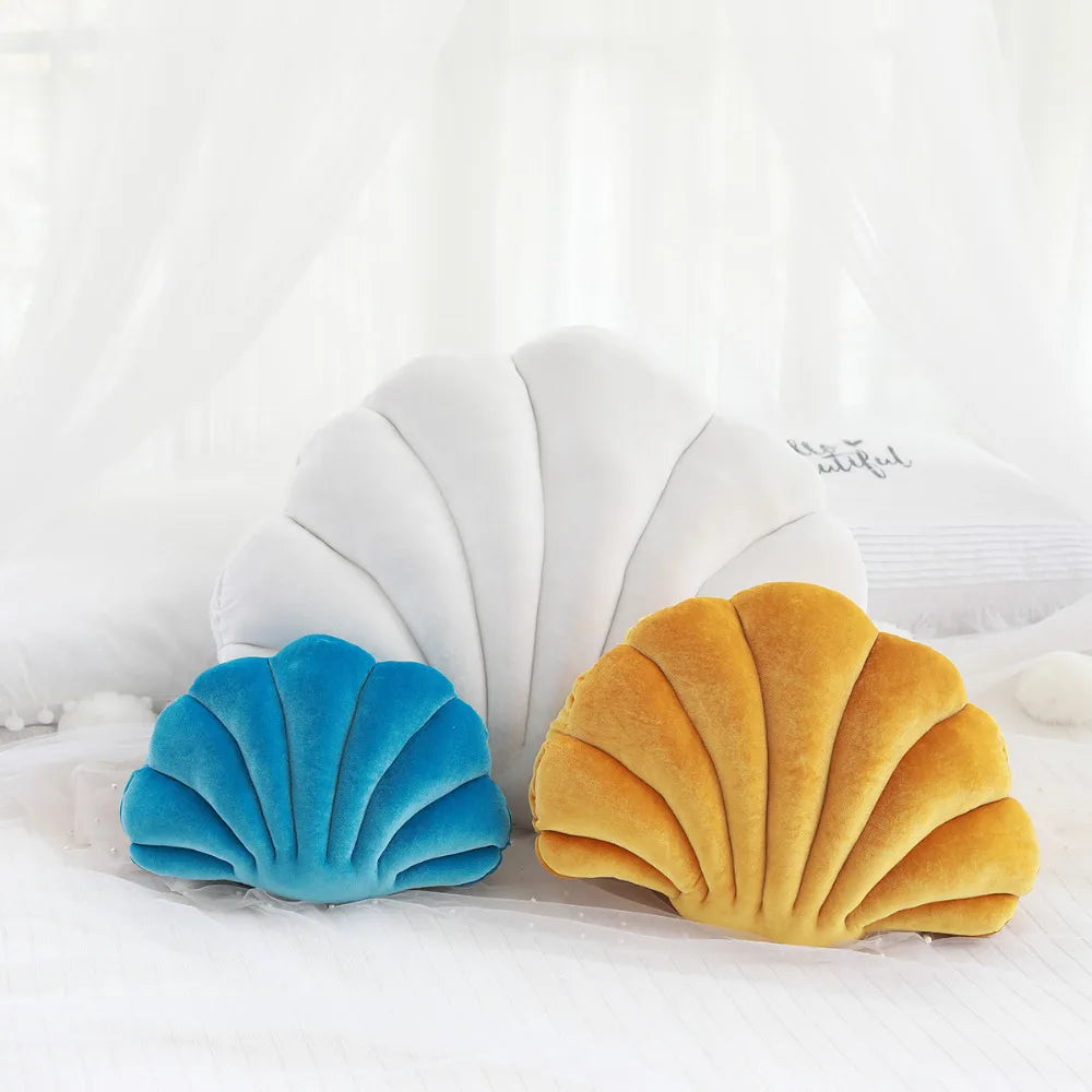 Two shell-shaped kawaii cushions, one blue and one yellow, on a white background.