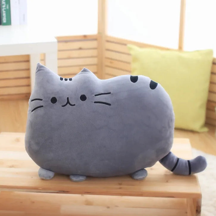 Plush cat-shaped kawaii pillow on a wooden surface with a blurred background