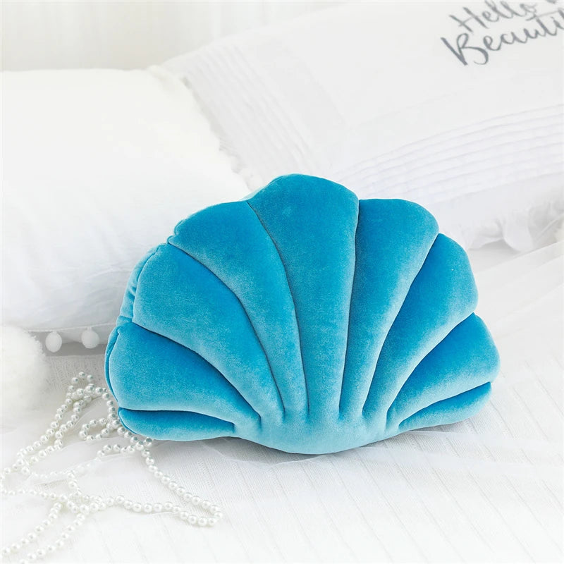 Blue shell-shaped kawaii pillow on a white surface with 'Hello Beautiful' text in the background