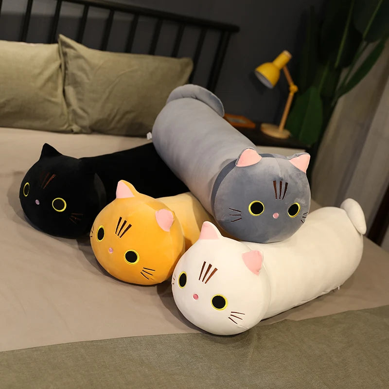 Four cat-shaped kawaii cushions in black, orange, gray, and white on a bed.