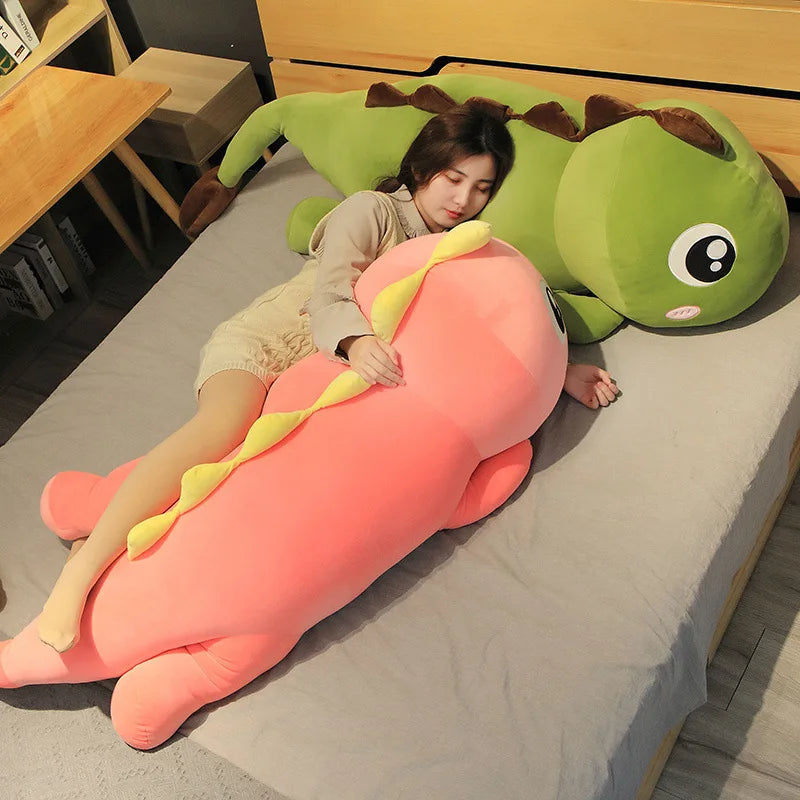 Person lying on a large, colorful caterpillar-shaped kawaii pillow on a bed.