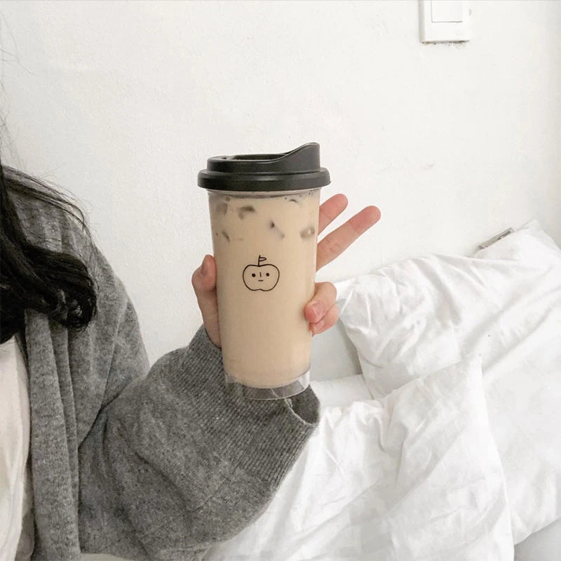 Person holding a Kawaii coffee cup with a black lid and a small design on a white background