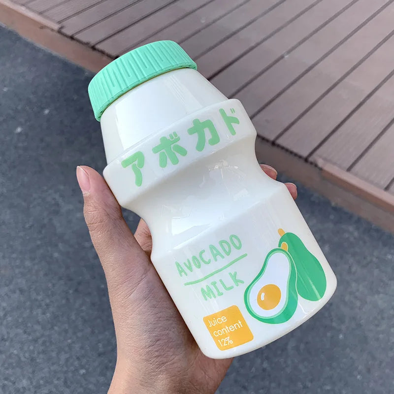 Hand holding a Kawaii bottle of avocado milk with green cap and avocado illustration on label.