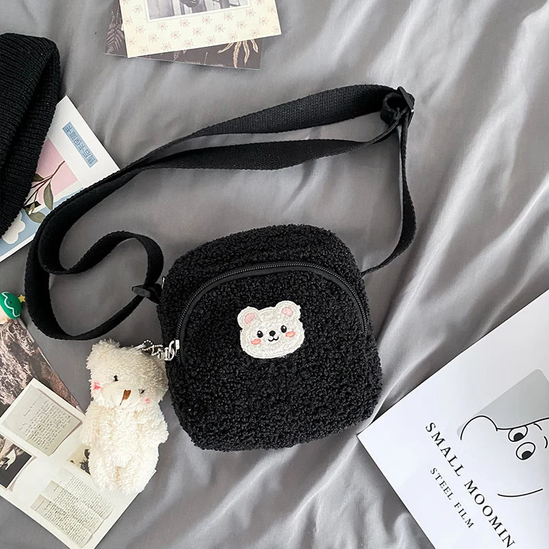 Black plush bag with a Kawaii bear design on a gray surface with books and a small plush toy.