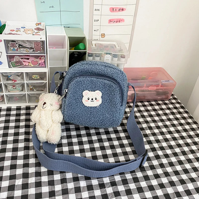 Blue textured bag with a Kawaii bear emblem on a checkered tablecloth, next to a small plush toy.