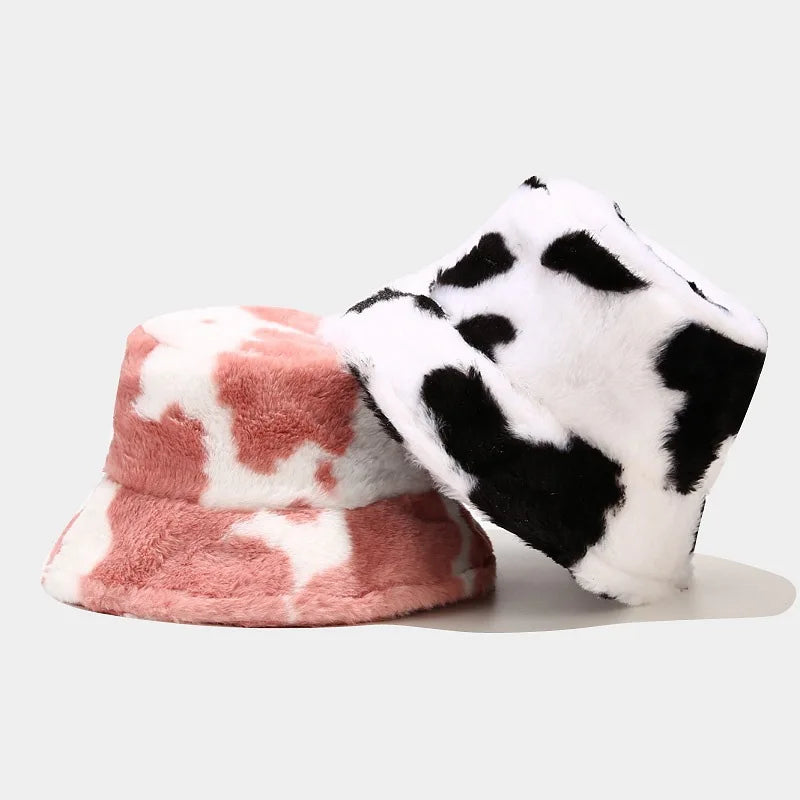 Two plush Kawaii hats with cow print pattern on a light gray background