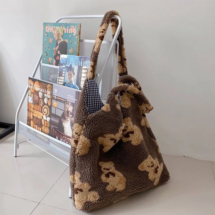 Brown kawaii teddy bear-patterned bag leaning against a magazine rack with books on a white floor.
