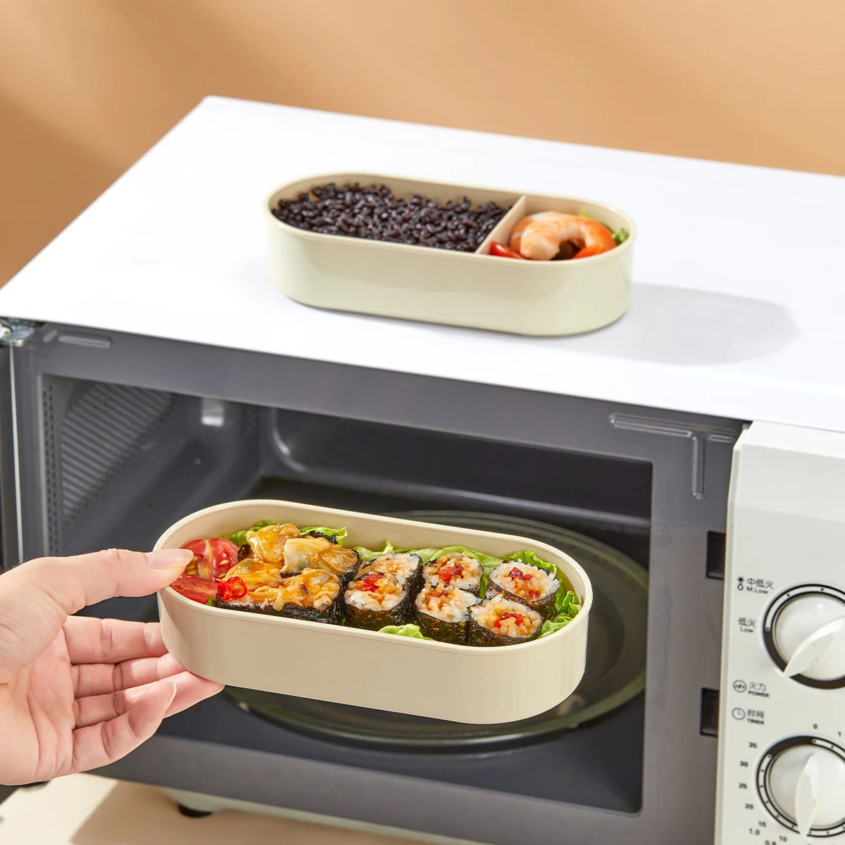 Kawaii-style beige compartmentalized food container being used in a microwave with food inside.